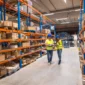 two warehouse workers walking distribution storage area discussing about logistics organization 2 85x85